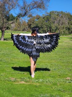 a woman is walking in the grass with a black and white shawl over her shoulders