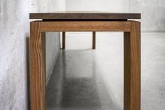 a wooden table sitting in the middle of a room next to a white brick wall