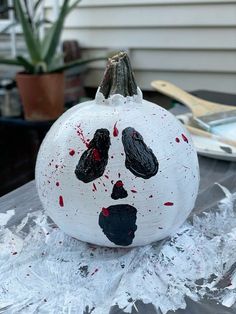 a white painted pumpkin with black and red splatters on it's face