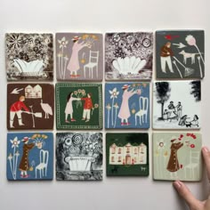 a hand is pointing at several small tiles with different designs on them, including people and animals