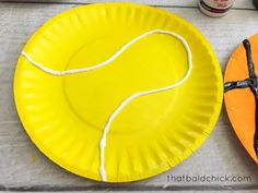 a paper plate with a tennis ball on it next to an orange and black plate