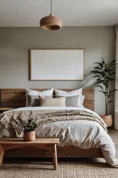 a bedroom with a large bed and plants on the side table in front of it