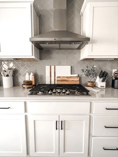 a stove top oven sitting inside of a kitchen next to white cupboards and drawers