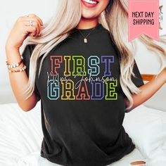 a woman with blonde hair wearing a black shirt that says first grade on the front