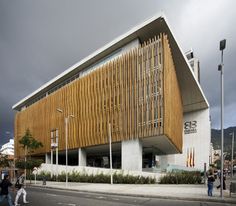 people walking on the sidewalk in front of a building with wooden slats covering it