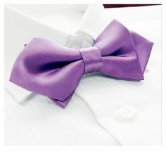 a close up of a purple bow tie on a white shirt