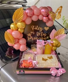 a pink and gold birthday party with balloons, food and decorations on the back of a car