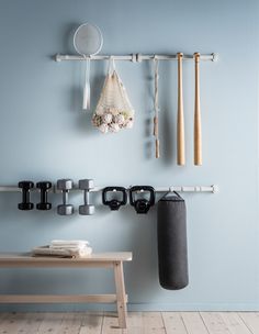 there is a rack with sports equipment hanging on the wall next to a bench and table