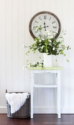 a white table with flowers and a clock on the wall