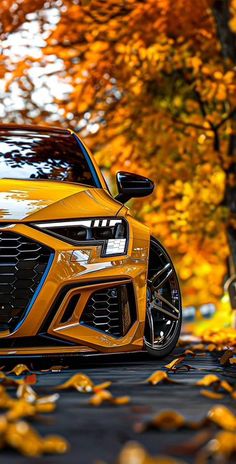 an orange sports car parked in front of some trees