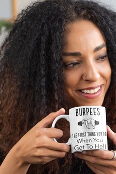 a woman holding a coffee mug with the words burpees on it in front of her face