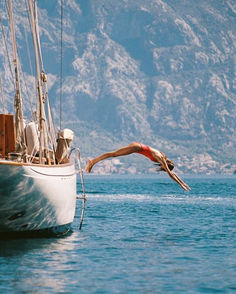 a man dives into the water from a sailboat