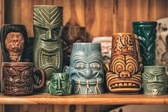 many different colored ceramic mugs on a shelf