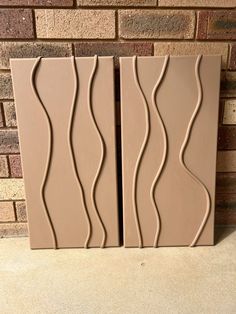 two brown tiles sitting on top of a counter next to a brick wall with wavy lines