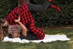 a man and woman laying on top of each other in the grass