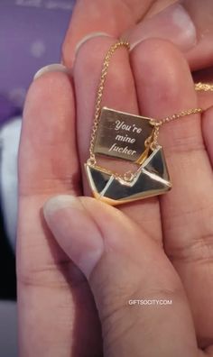 a person holding a gold necklace with an envelope on it that says, you're mine