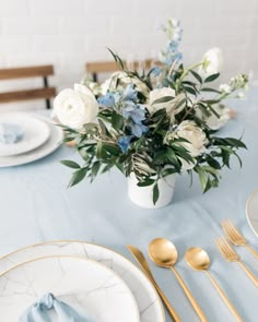 a table set with white and blue flowers in a vase