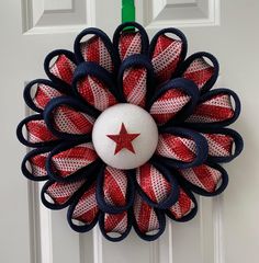 a red, white and blue mesh wreath with a star on it hanging from the front door