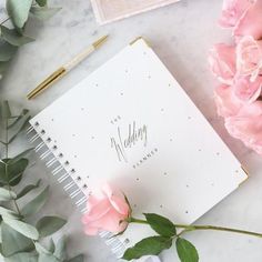 a notebook with writing on it next to pink flowers