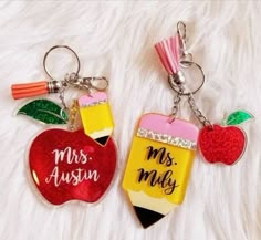 two key chains with an apple and pencil on them