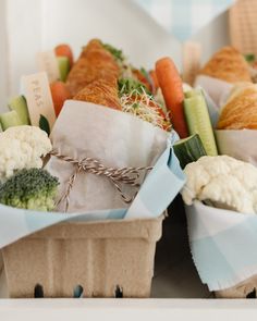 two baskets filled with different types of food on top of a white tablecloth covered counter