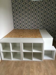 a room with some shelves and a lamp on the wall next to it in front of a decorative wall