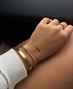 a woman's arm with two gold bracelets on top of her left arm