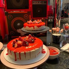 two cakes with strawberries on top and red sauce drizzled over them