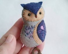 a small stuffed owl sitting on top of a keychain in someone's hand