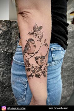 a woman's arm with a bird and flowers tattoo on the left side of her body