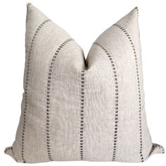 a gray and white pillow with black stitching on the front, sitting against a white background