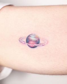 a small saturn tattoo on the back of a woman's arm