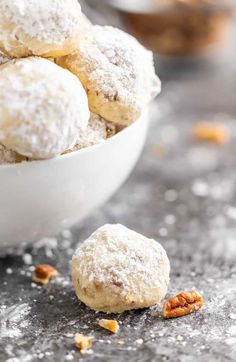 a white bowl filled with powdered sugar covered cookies