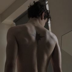 a man with a star tattoo on his back is looking at himself in the mirror