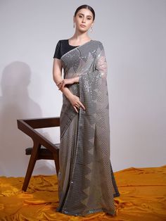 Add grace and charm to your appearance in this charming grey color saree made of heavy georgette material embellished with sequins embroidery work all over. The pretty grey sequin saree comes with a similar color blouse made of mono banglori material. This grey festival wear saree comes with a 5.50-meter long and stitched 1.00-meter blouse material. Add the blowing vibrancy of the season to your wardrobe with this grey sequin georgette saree for your upcoming party, functions, festival, occasion Georgette Material, Sequin Saree, Grey Saree, Ruffle Saree, Color Blouse, Readymade Saree, Ethnic Sarees, Saree Trends, Embellished Blouse