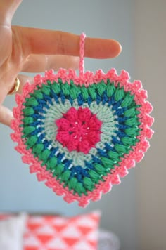 someone is holding up a crocheted heart ornament