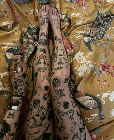 two tattooed legs laying on top of a bed next to each other with tattoos all over them