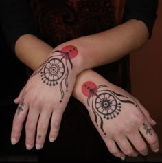 two women with matching tattoos on their arms and hands, both holding each other's hand