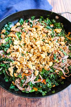 a pan filled with noodles and vegetables on top of a wooden table