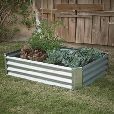 a raised garden bed in the yard with vegetables growing out of it's sides