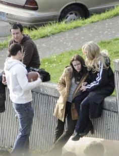 three people are sitting on a wall talking to each other