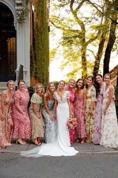 a group of women standing next to each other in front of a building and trees