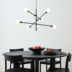 a dining room table with black chairs and a bowl of fruit on the table in front of it