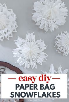 paper snowflakes hanging from the ceiling with text overlay that reads easy diy paper bag snowflakes