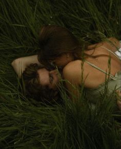 a man and woman are laying in the grass with their heads close to each other