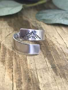 "This listing is for one 1/4\" wide 14 gauge aluminum wrap ring hand stamped with mountains. This can also be stamped with a name up to 9 letters. Please include in the message to seller section the name to be stamped if you would like to add one. Please also take note that it is not recommended to wear these rings in contact with water or any washing products to avoid the darkened letters to fade away. This lightweight aluminum adjustable wrap ring is 1/4 inches wide and is created from pure hi Grandmas Jewelry, Silver Smithing, Mountain Ring, Ring Wrap, Stamped Ring, Hand Stamped Ring, Metal Stamped Jewelry, Unique Silver Jewelry, Stamped Rings