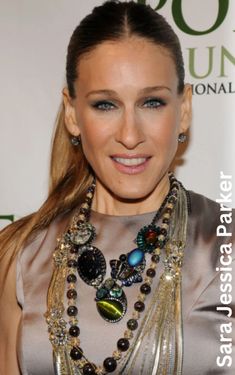 a woman with long hair wearing a silver dress and some necklaces on her neck