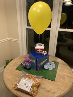 a table topped with a box and yellow balloon