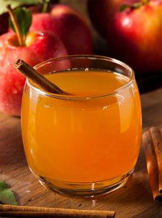 an apple cider with cinnamon sticks and apples in the background