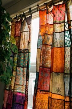 the curtains are hanging in front of the window with many different colored fabrics on them